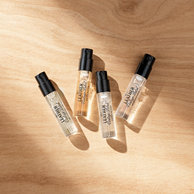 Four bottles of leather perfume roll-on on a wooden surface