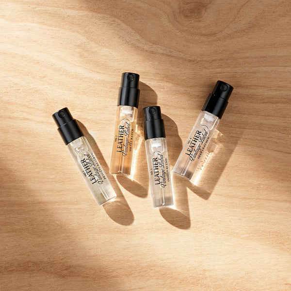 Four bottles of leather perfume roll-on on a wooden surface