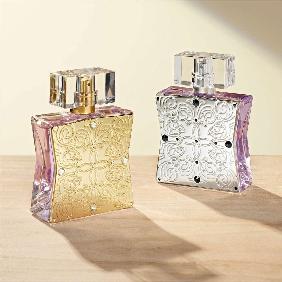 Two ornate perfume bottles on a light wooden surface with a soft beige background