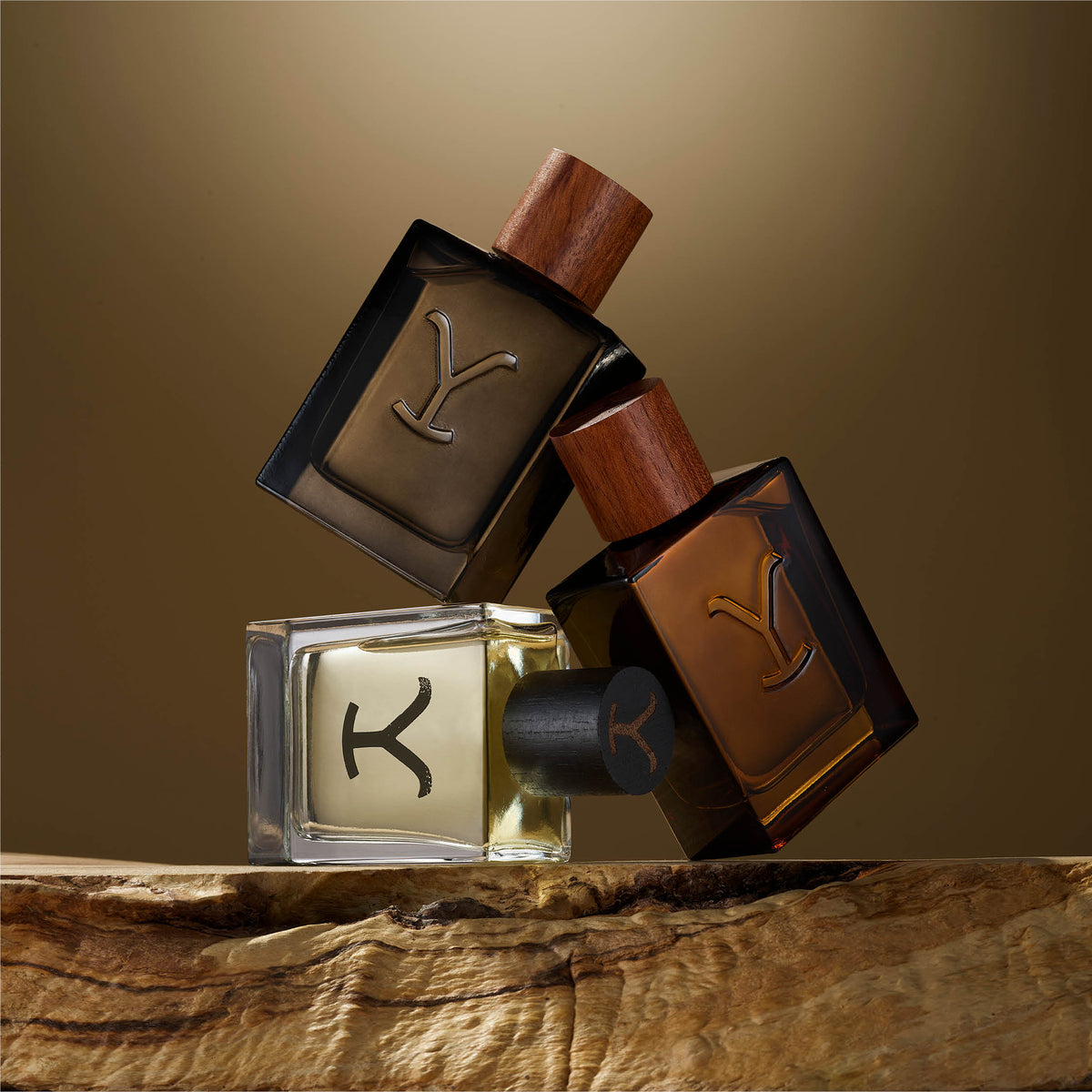 Three YSL perfume bottles on a wooden surface with a brown background