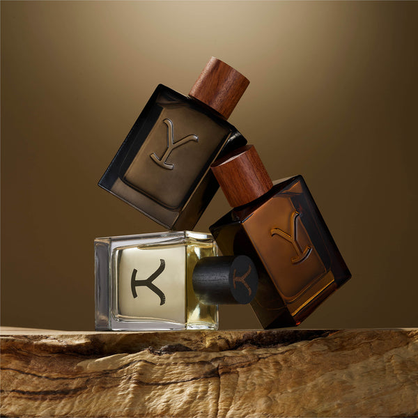 Three YSL perfume bottles on a wooden surface with a brown background