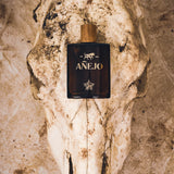 Anejo Perfume bottle on a textured stone surface