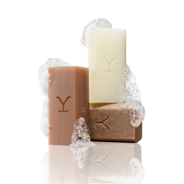 Two bars of soap with a candle on a white background