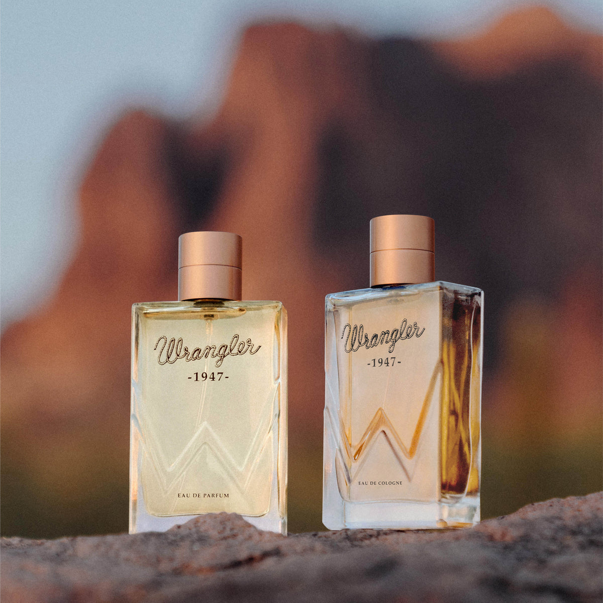 Two bottles of Wrangler 1947 perfume against a blurred natural background